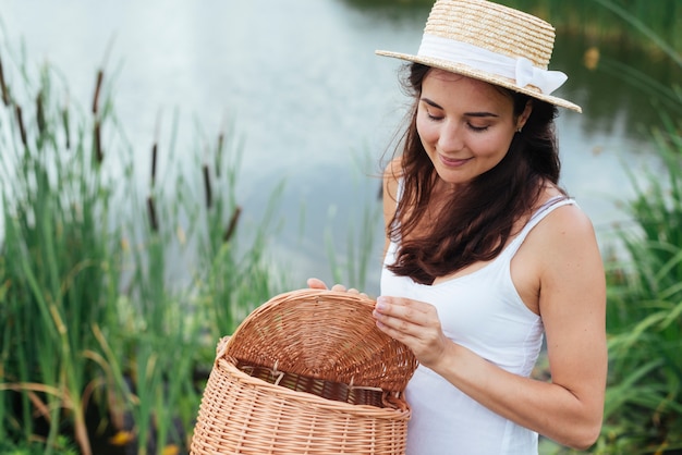Frau hält Picknickkorb am See