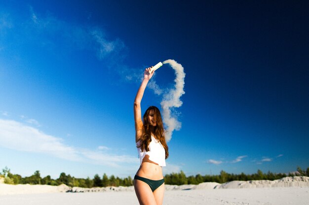 Frau hat Spaß mit Sand auf dem Wind unter blauem Himmel