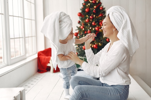 Frau hat Spaß, sich auf Weihnachten vorzubereiten. Mutter in einem weißen Hemd spielt mit ihrer Tochter. Die Familie ruht sich in einem festlichen Raum aus.