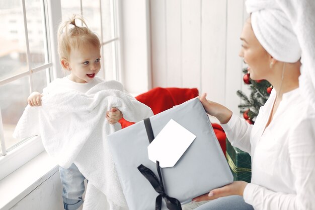 Frau hat Spaß, sich auf Weihnachten vorzubereiten. Mutter in einem weißen Hemd spielt mit ihrer Tochter. Die Familie ruht sich in einem festlichen Raum aus.