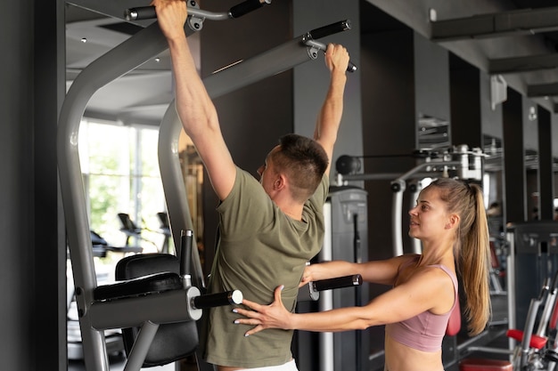 Frau hilft Mann bei Seitenansicht im Fitnessstudio