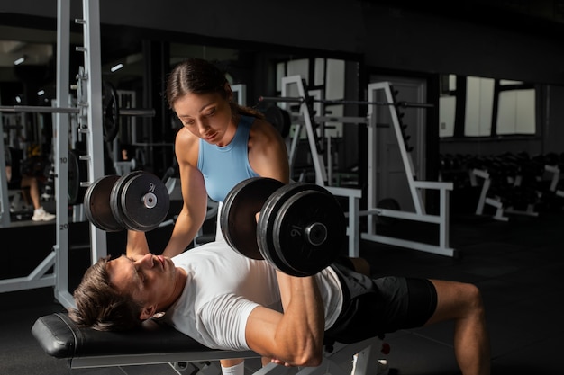 Kostenloses Foto frau hilft mann im fitnessstudio