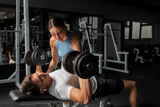 Frau hilft Mann im Fitnessstudio