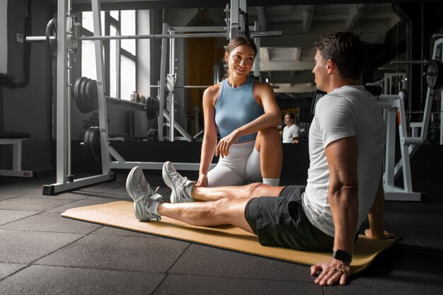 Frau hilft Mann im Fitnessstudio