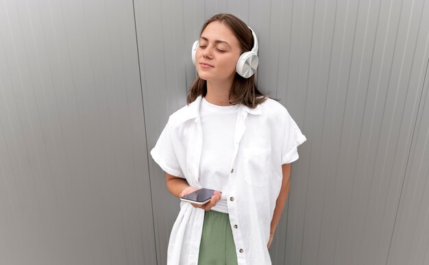 Frau hört Musik über ihre Kopfhörer, während sie ihr Smartphone hält