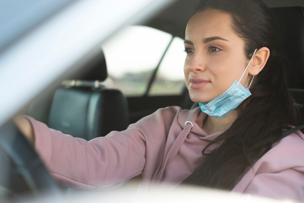 Frau im Auto benutzt die Maske nicht richtig