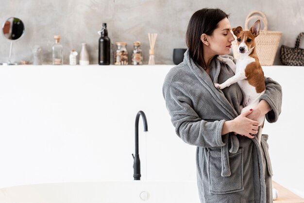 Frau im Badezimmer hält ihren Hund