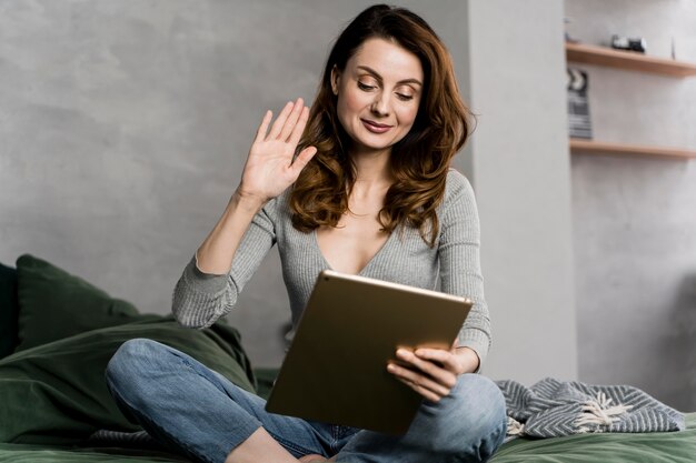 Frau im Bett, die mit Tablette strömt