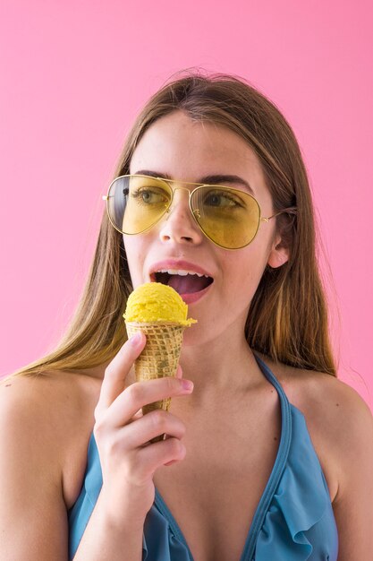 Frau im Bikini mit Eiscreme und Sonnenbrille