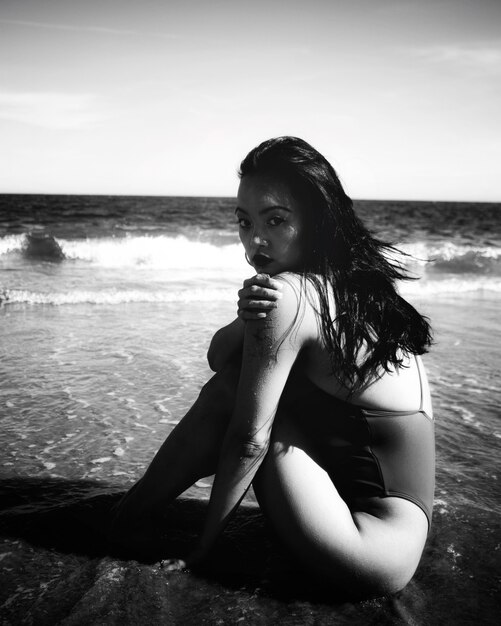 Frau im Bikini sitzt am Strand