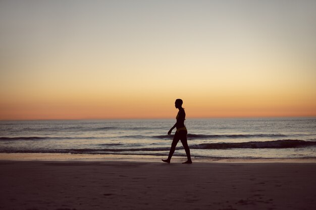 Frau im Bikini zu Fuß am Strand