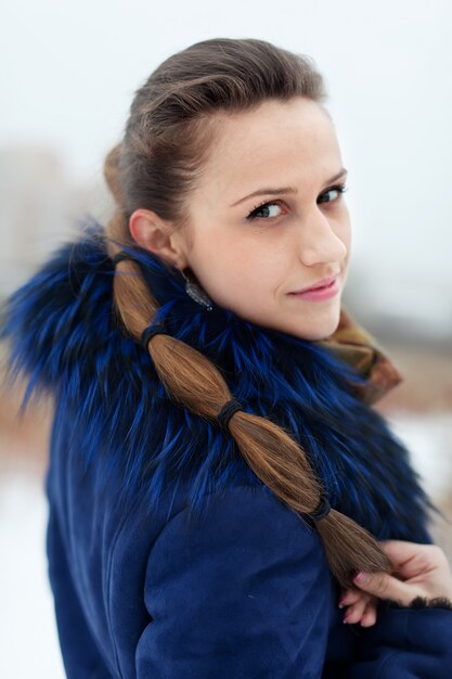 Frau im blauen Mantel im winterlichen Park