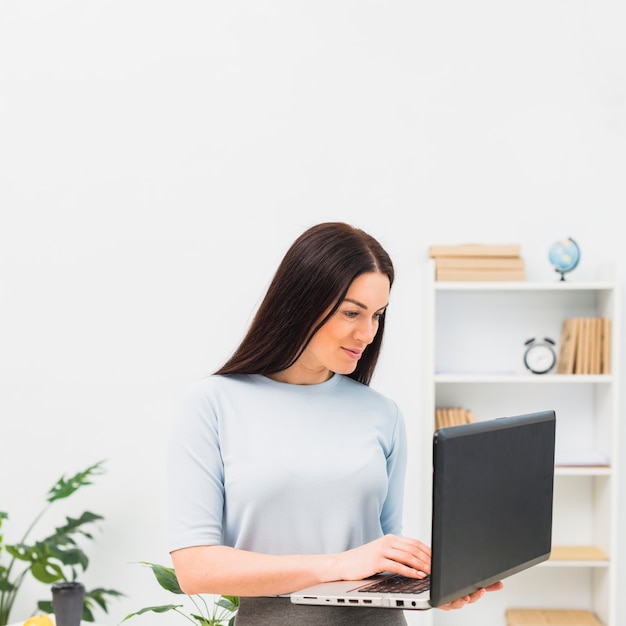 Frau im blauen Schreiben auf Laptoptastatur