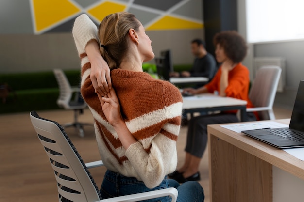 Frau im Büro, die sich während eines Arbeitstages dehnt