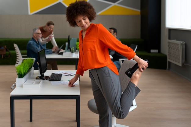 Frau im Büro, die sich während eines Arbeitstages dehnt