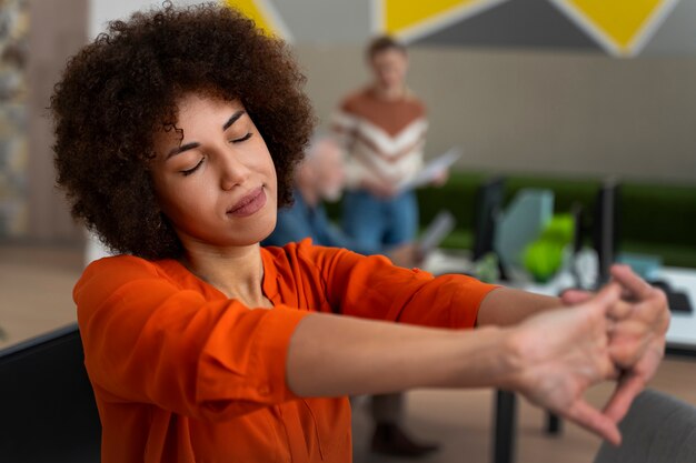 Frau im Büro, die sich während eines Arbeitstages dehnt