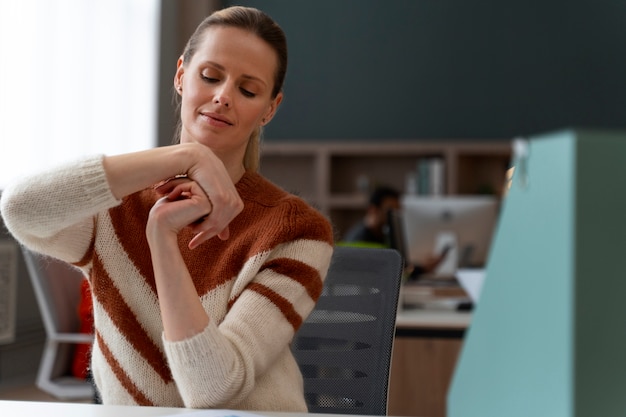 Kostenloses Foto frau im büro, die sich während eines arbeitstages dehnt