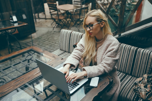 Frau im Café mit Laptop und Telefon