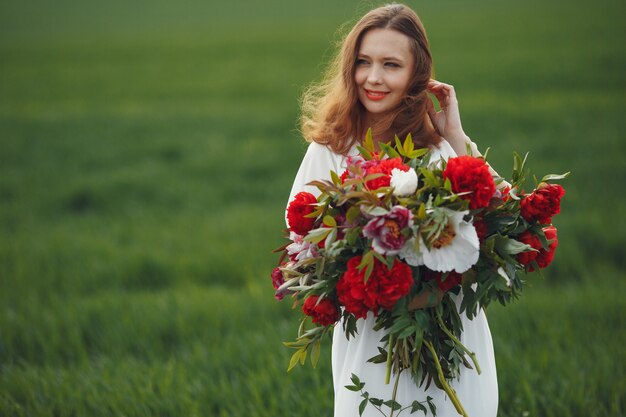 Frau im eleganten Kleid, das in einem Sommerfeld steht