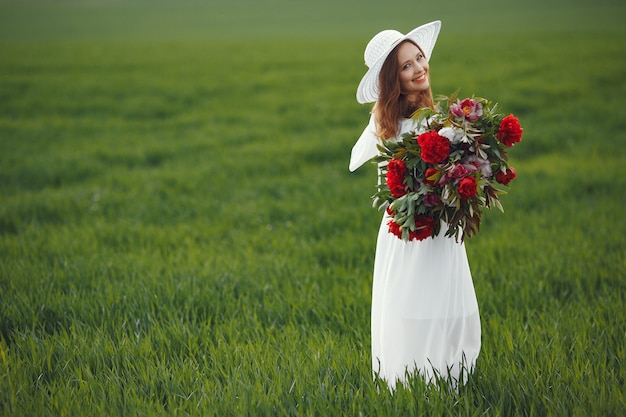 Frau im eleganten Kleid, das in einem Sommerfeld steht