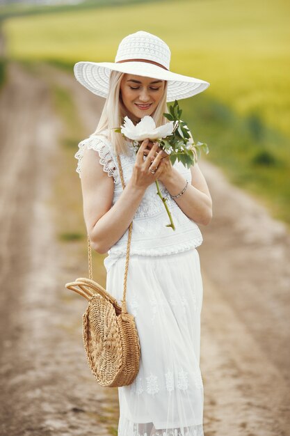 Frau im eleganten Kleid, das in einem Sommerfeld steht