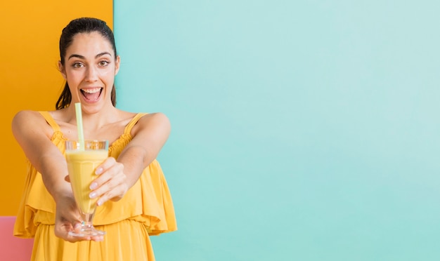 Frau im gelben Kleid mit einem Glas Saft