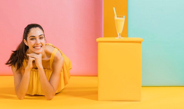 Frau im gelben Kleid mit einem Glas Saft