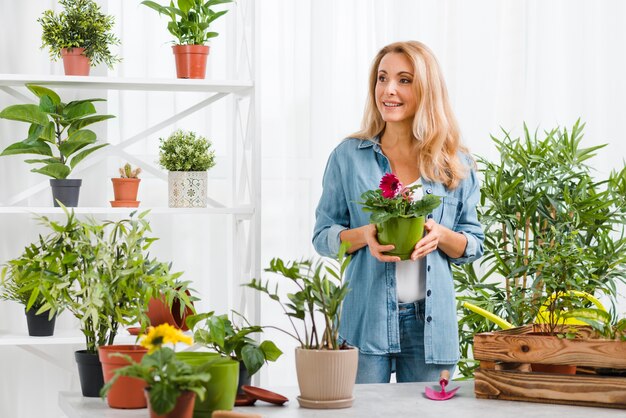 Frau im Gewächshaus, das Blumentopf hält