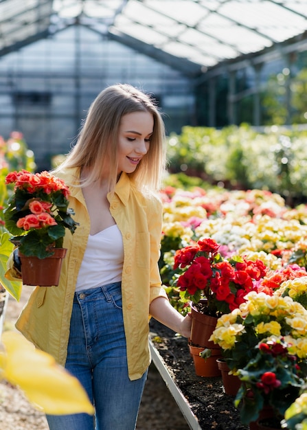 Frau im Gewächshaus, das um Blumen sich kümmert