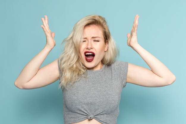 Frau im grauen Hemd und in den hellen blauen Jeans, die mit emotionalem Ausdruck aufwerfen