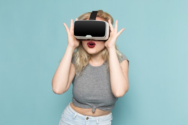 Frau im grauen Hemd und in den hellen blauen Jeans, die vr spielen