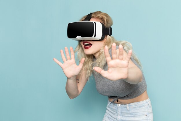 Frau im grauen Hemd und in den hellen blauen Jeans, die vr spielen