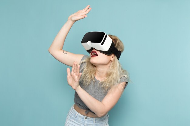 Frau im grauen Hemd und in den hellen blauen Jeans, die vr spielen