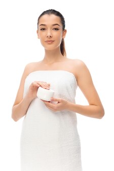 Frau im handtuch mit kosmetikprodukt auf weiß Premium Fotos