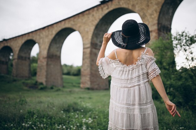 Frau im Hut durch Eisenbahnbrücke