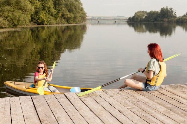 Frau im Kajak mit Freund, der Paddel auf Dock hält