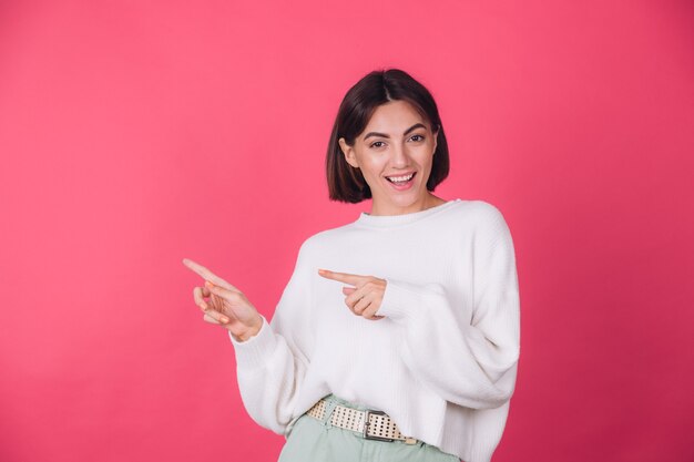 Frau im lässigen weißen Pullover an der roten Wand