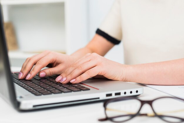 Frau im Licht, das auf Laptoptastatur schreibt