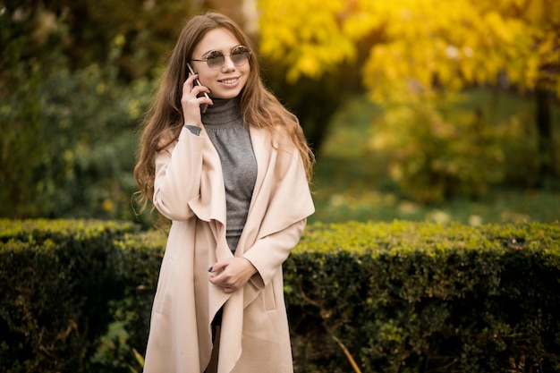 Frau im Mantel mit Telefon