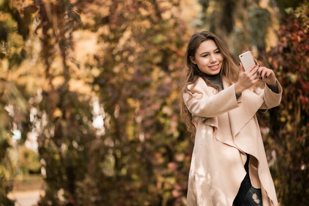 Frau im Mantel mit Telefon