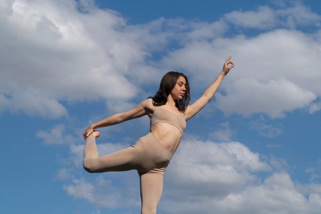 Frau im niedrigen Winkel, die draußen Yoga macht