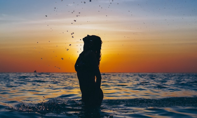 Frau im Ozean in der Sonnenuntergangzeit