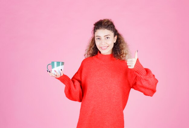 Frau im roten Hemd, die eine Kaffeetasse hält und den Geschmack genießt.