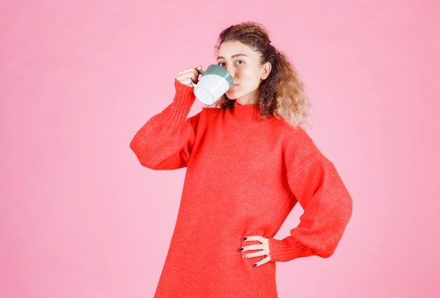 Frau im roten hemd, die eine tasse kaffee trinkt.