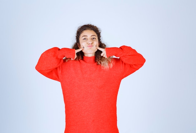 Frau im roten Sweatshirt, die lächelnde und verführerische Posen gibt.