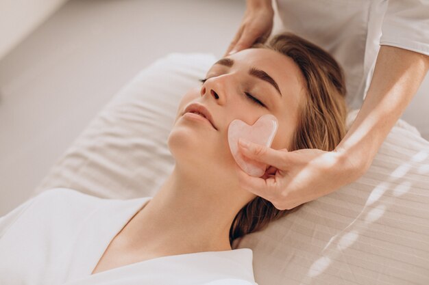 Frau im Salon macht Schönheitsbehandlung mit Gua-Sha-Stein