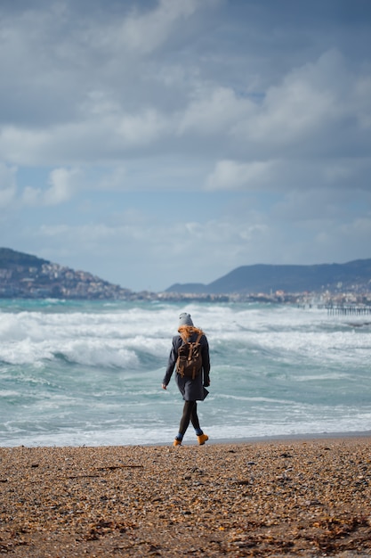Frau im schwarzen Kleid, die tagsüber vor seinem Strand steht