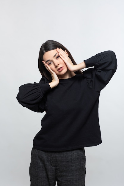 Frau im schwarzen Pullover zeigt Kopfschmerzen