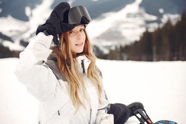 Frau im Snowboardanzug. Sportlerin auf einem Berg mit einem Snowboard in den Händen am Horizont. Konzept zum Sport