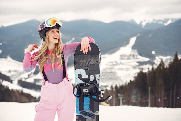 Frau im Snowboardanzug. Sportlerin auf einem Berg mit einem Snowboard in den Händen am Horizont. Konzept zum Sport